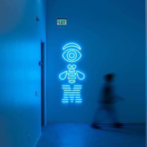 neon rebus in hallway with person walking nearby